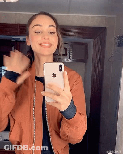 A Woman Is Taking A Picture Of Herself With Her Iphone GIF
