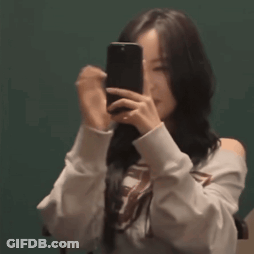 A Woman Is Taking A Picture Of Herself With Her Phone . GIF