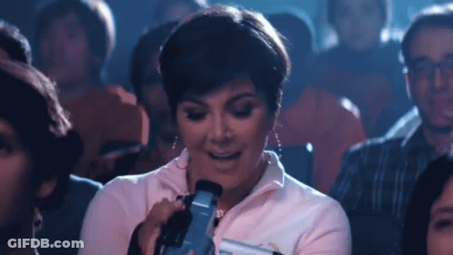 A Woman Is Taking A Picture With A Camera In A Crowded Theater GIF