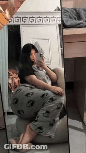 A Woman Is Taking A Selfie In Front Of A Mirror With Chinese Characters On It GIF