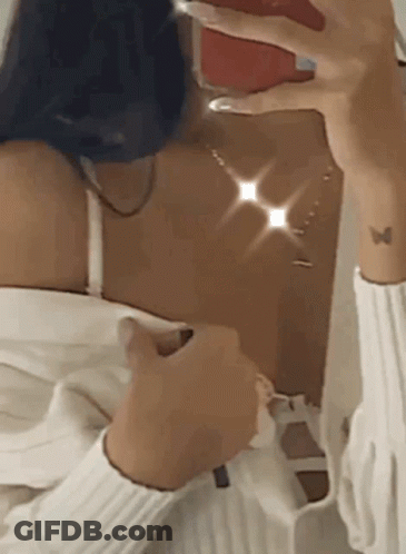 A Woman Is Taking A Selfie In Front Of A Mirror With Her Phone . GIF