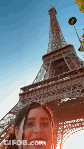 A Woman Is Taking A Selfie In Front Of The Eiffel Tower In Paris GIF