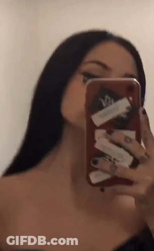 A Woman Is Taking A Selfie In The Mirror With Her Cell Phone . GIF
