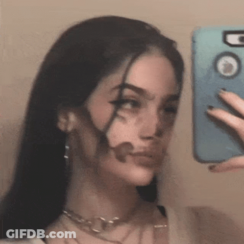 A Woman Is Taking A Selfie In The Mirror With Her Face Painted Black . GIF