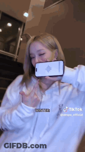 A Woman Is Taking A Selfie With A Cell Phone In Her Hand . GIF