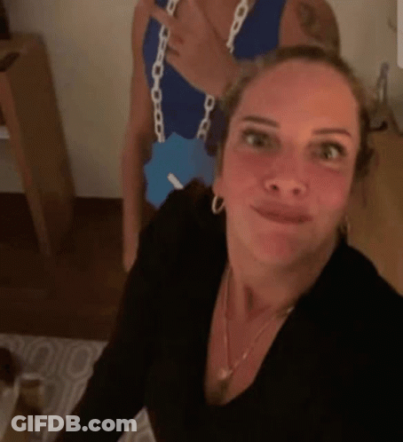 A Woman Is Taking A Selfie With A Man In A Blue Tank Top . GIF