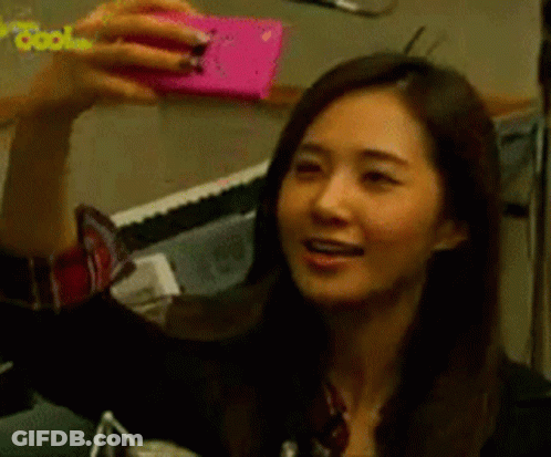 A Woman Is Taking A Selfie With A Pink Cell Phone GIF