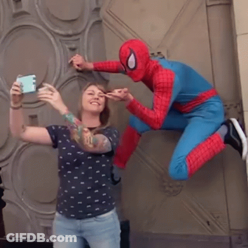 A Woman Is Taking A Selfie With A Spider Man In A Spiderman Costume GIF