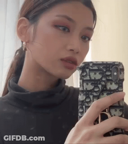 A Woman Is Taking A Selfie With Her Cell Phone . GIF