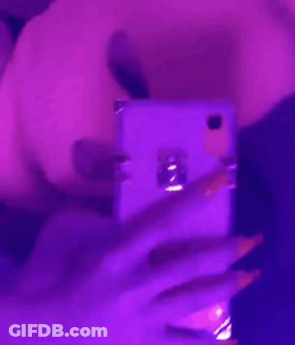A Woman Is Taking A Selfie With Her Cell Phone In A Purple Light . GIF