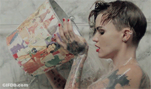 A Woman Is Taking A Shower And Holding A Bucket With A Picture On It GIF