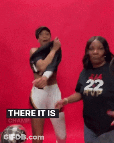 A Woman Is Taking Off Her Shirt While Standing Next To Another Woman In A Black Shirt With The Number 22 On It . GIF