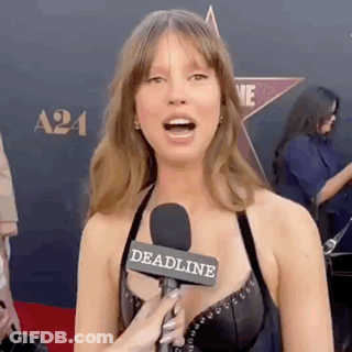 A Woman Is Talking Into A Microphone On A Red Carpet At An Event . GIF