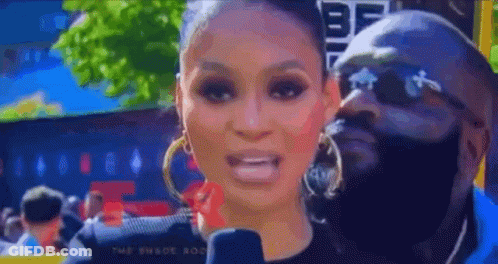 A Woman Is Talking Into A Microphone While A Man Is Behind Her . GIF