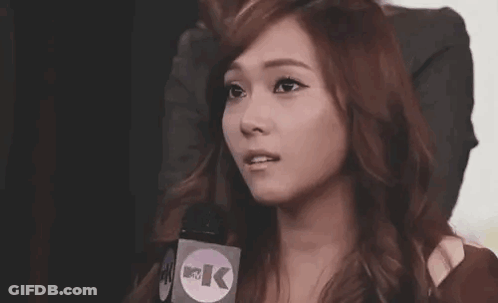 A Woman Is Talking Into A Microphone While Making A Funny Face . GIF