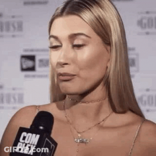 A Woman Is Talking Into A Microphone While Wearing A Choker Necklace . GIF