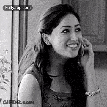 A Woman Is Talking On A Cell Phone And Smiling . GIF