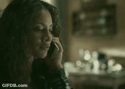 A Woman Is Talking On A Cell Phone In Front Of A Table . GIF