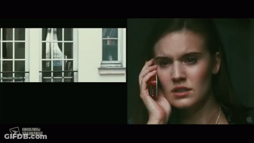 A Woman Is Talking On A Cell Phone In Front Of A Window With Russian Writing On The Bottom GIF