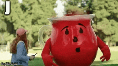A Woman Is Talking On A Cell Phone Next To A Large Red Pitcher With Arms And Legs . GIF