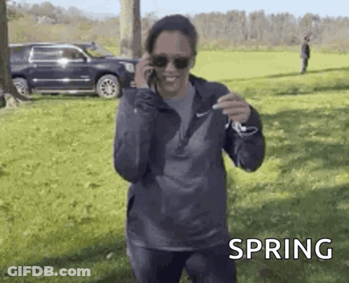 A Woman Is Talking On A Cell Phone While Standing In A Field . GIF