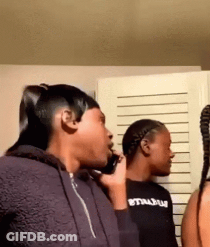 A Woman Is Talking On A Cell Phone While Standing Next To Another Woman In A Room . GIF