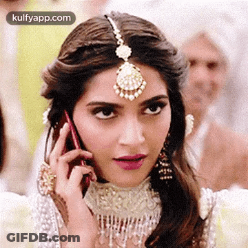 A Woman Is Talking On A Cell Phone While Wearing A Headpiece . GIF
