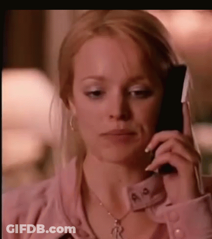 A Woman Is Talking On A Cell Phone While Wearing A Pink Shirt And A Necklace . GIF