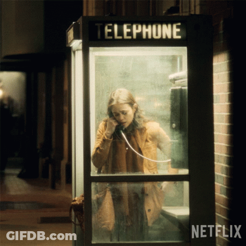 A Woman Is Talking On A Phone In A Telephone Booth With Netflix Written On The Bottom GIF