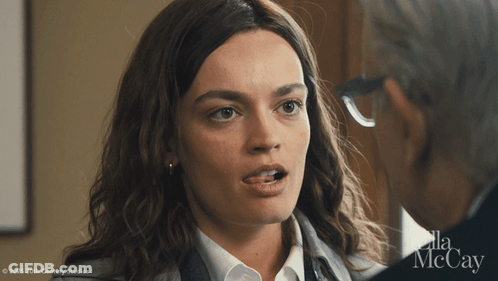 A Woman Is Talking To A Man With Ella Mccay Written On The Bottom GIF