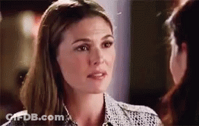 A Woman Is Talking To Another Woman While Looking At Her Face . GIF
