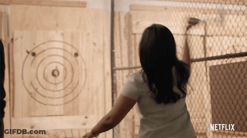 A Woman Is Throwing An Axe At A Target That Says Netflix GIF