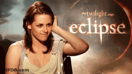 A Woman Is Touching Her Hair In Front Of A Poster For The Twilight Saga Eclipse . GIF