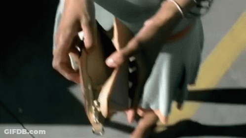 Woman Tying Shoes In Parking Lot Wearing Skirt GIF