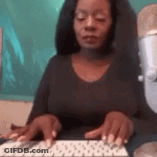 A Woman Is Typing On A Keyboard With Her Eyes Closed . GIF