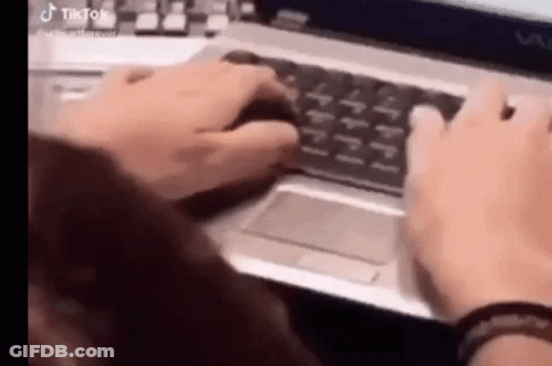 A Woman Is Typing On A Laptop Computer While Holding A Mouse . GIF