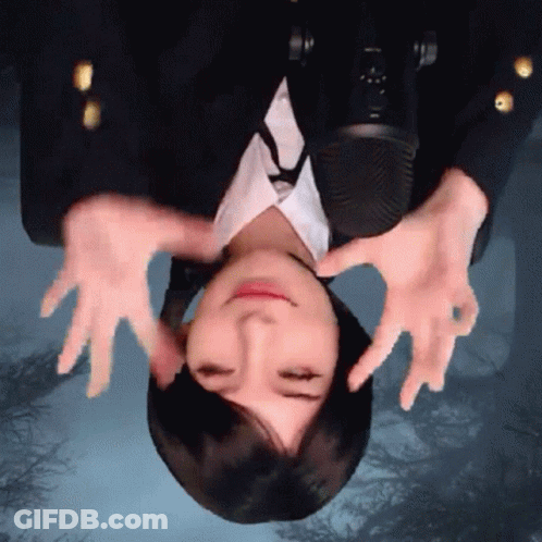 A Woman Is Upside Down In Front Of A Microphone With Her Hands On Her Face GIF