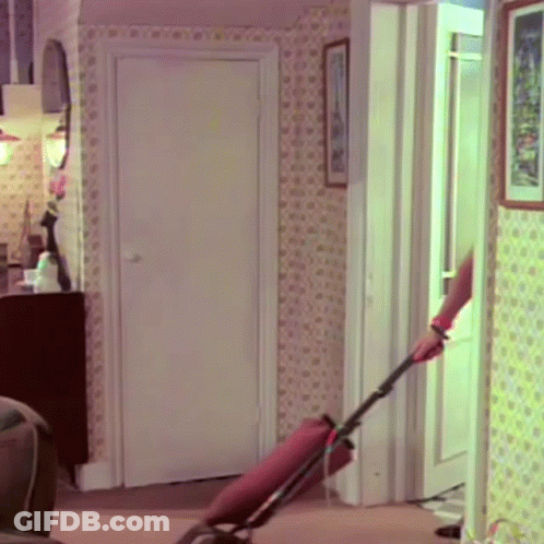 A Woman Is Using A Vacuum Cleaner In A Room GIF