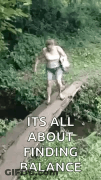 A Woman Is Walking Across A Small Wooden Bridge Over A Stream . GIF