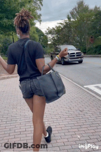 A Woman Is Walking Down A Brick Sidewalk With A Dodge Truck In The Background And The Word Imgplay At The Bottom GIF