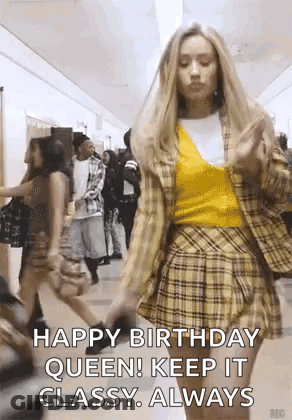 A Woman Is Walking Down A Hallway Wearing A Plaid Skirt And A Yellow Top . GIF