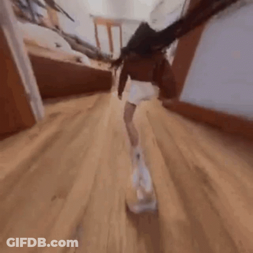 A Woman Is Walking Down A Hallway With A Dog In Her Hand . GIF