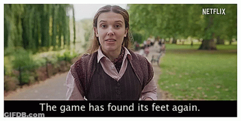 A Woman Is Walking Down A Path In A Park With The Words `` The Game Has Found Its Feet Again '' . GIF