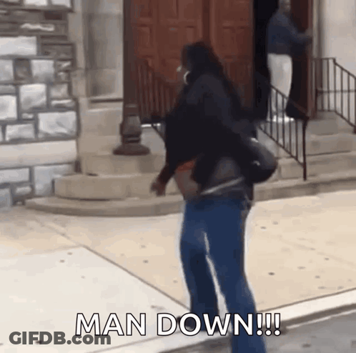 A Woman Is Walking Down A Sidewalk With The Words Man Down Written On The Ground . GIF