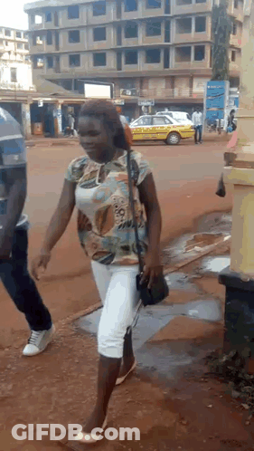 Woman Walking Down Street With Yellow Taxi GIF