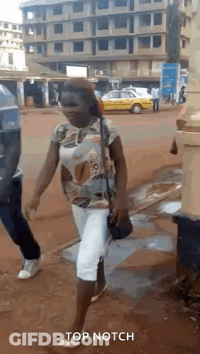 A Woman Is Walking Down A Street With The Words Top Notch Written On The Bottom GIF