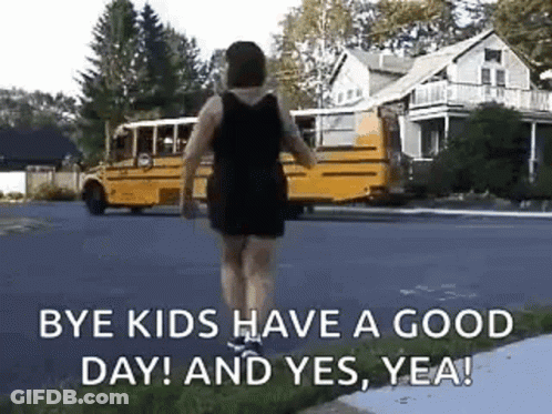 A Woman Is Walking Down The Street In Front Of A School Bus . GIF