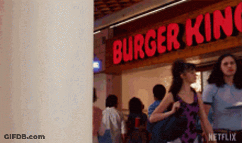 A Woman Is Walking In Front Of A Burger King Restaurant . GIF
