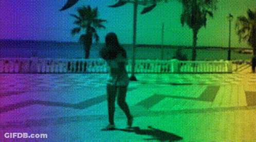 A Woman Is Walking On A Sidewalk With A Rainbow Background GIF