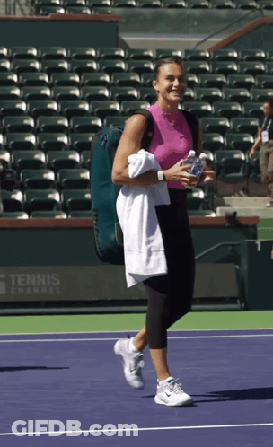 A Woman Is Walking On A Tennis Court With A Tennis Camp Sign In The Background GIF